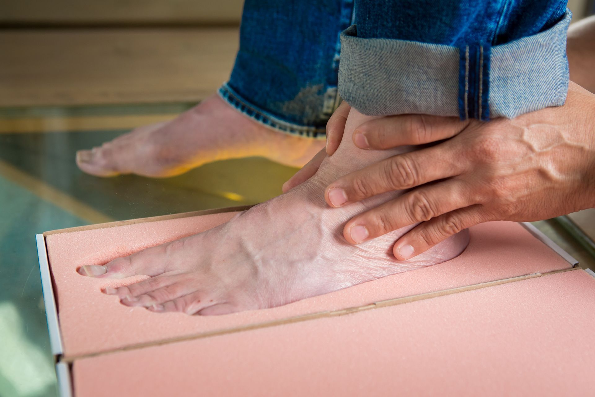 Een persoon meet de voet van een persoon met behulp van een horloge.