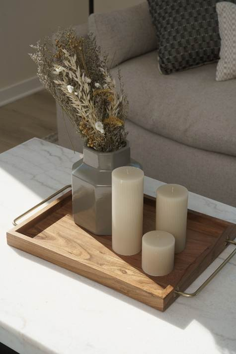 Photo of a candle set and a pot on a tray on a table.