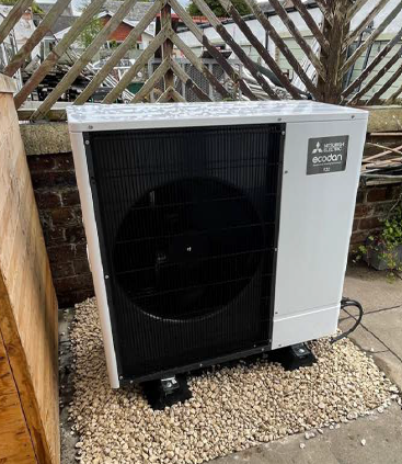 a white and black heat pump installation is sitting on top of a pile of gravel .