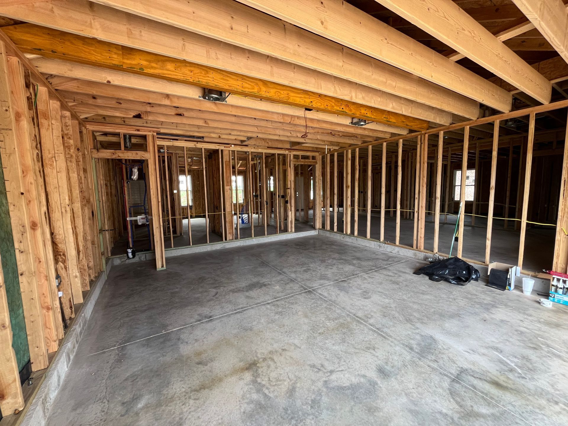 Interior view of a building under construction, framed with wooden studs and concrete floor.