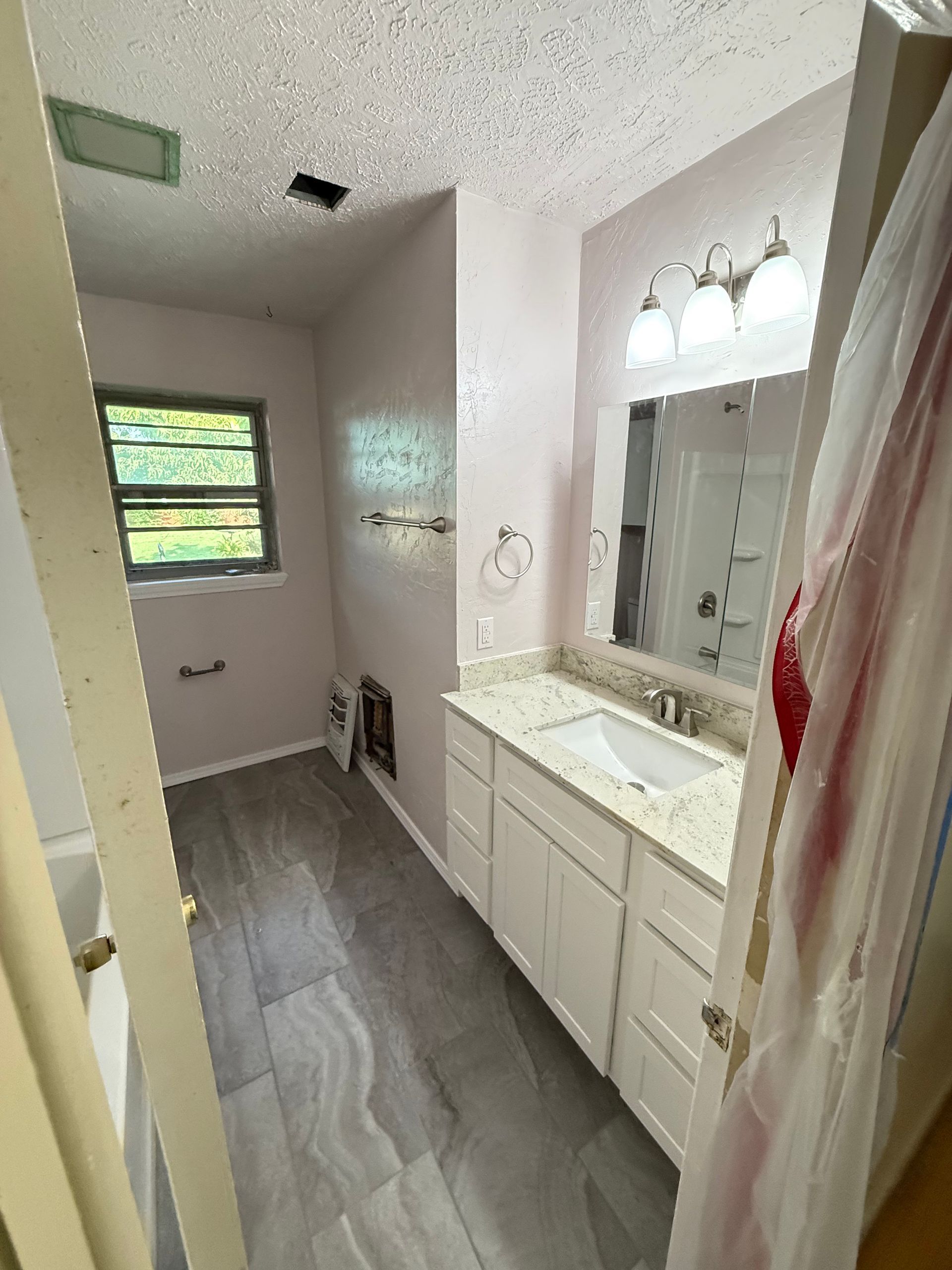 Bathroom with gray tile floor, white vanity with granite countertop, and pink walls.