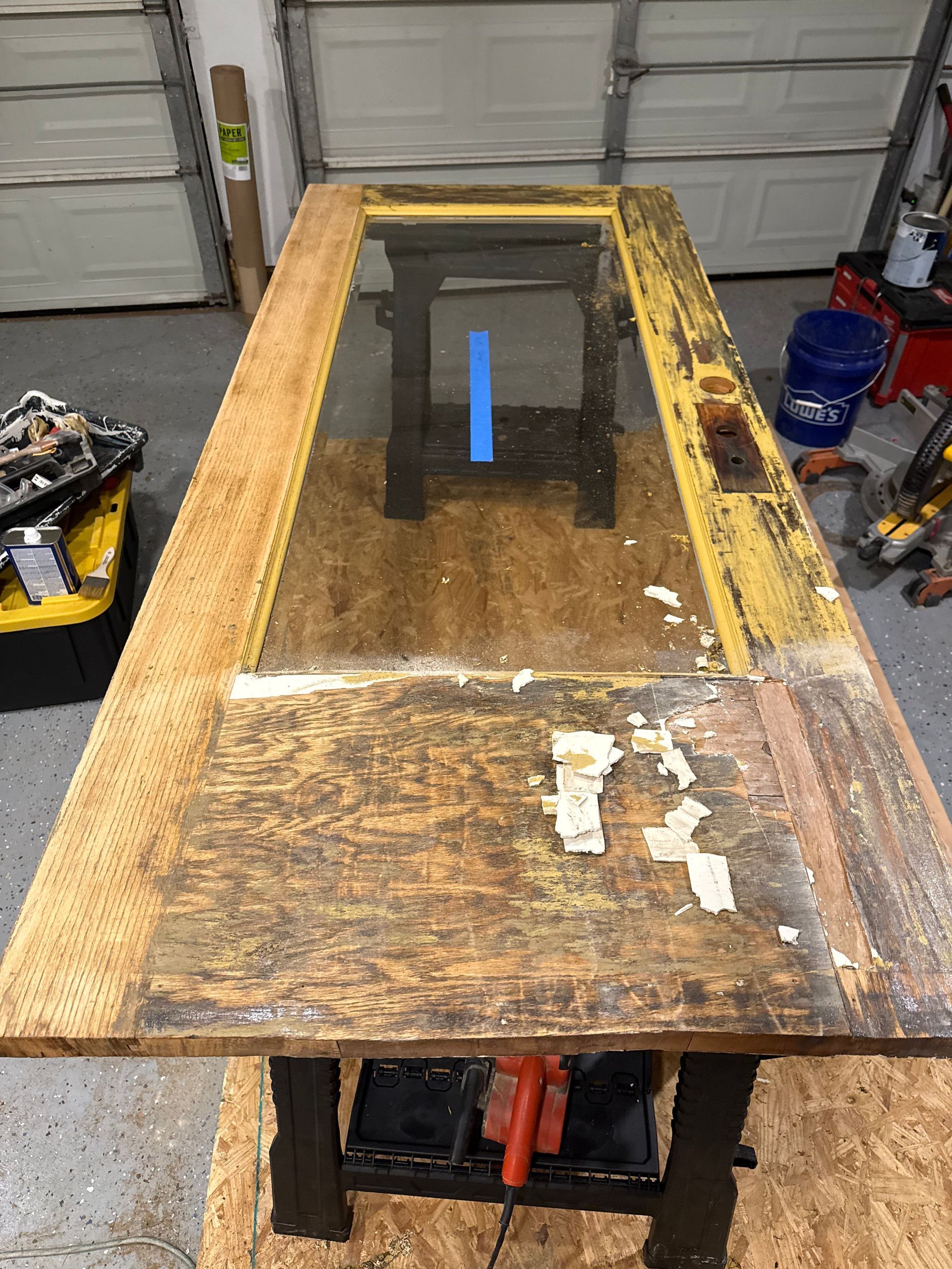 Door on a work table, paint peeling; garage setting.