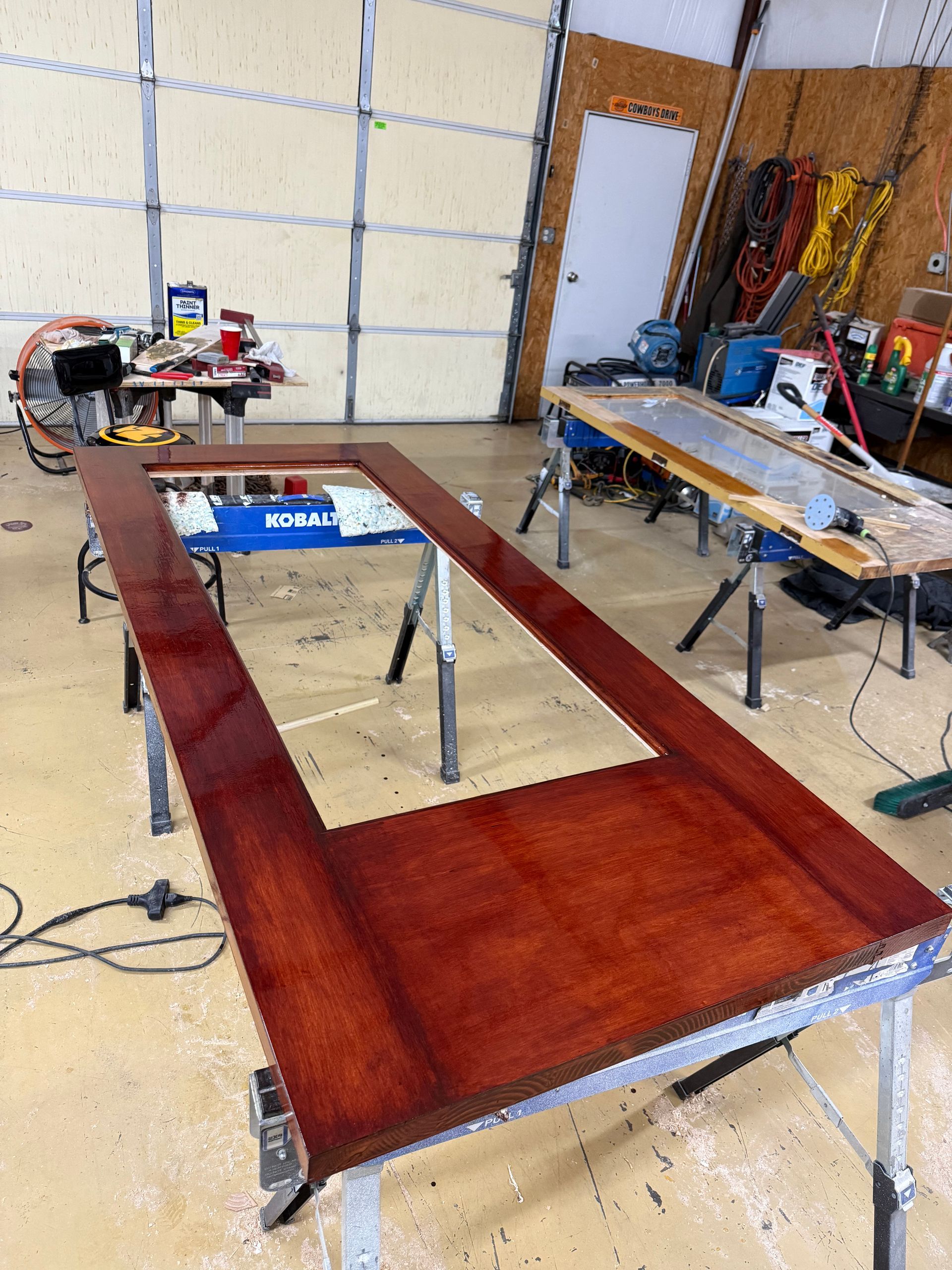 Finished, reddish-brown door frame on sawhorses in a workshop.