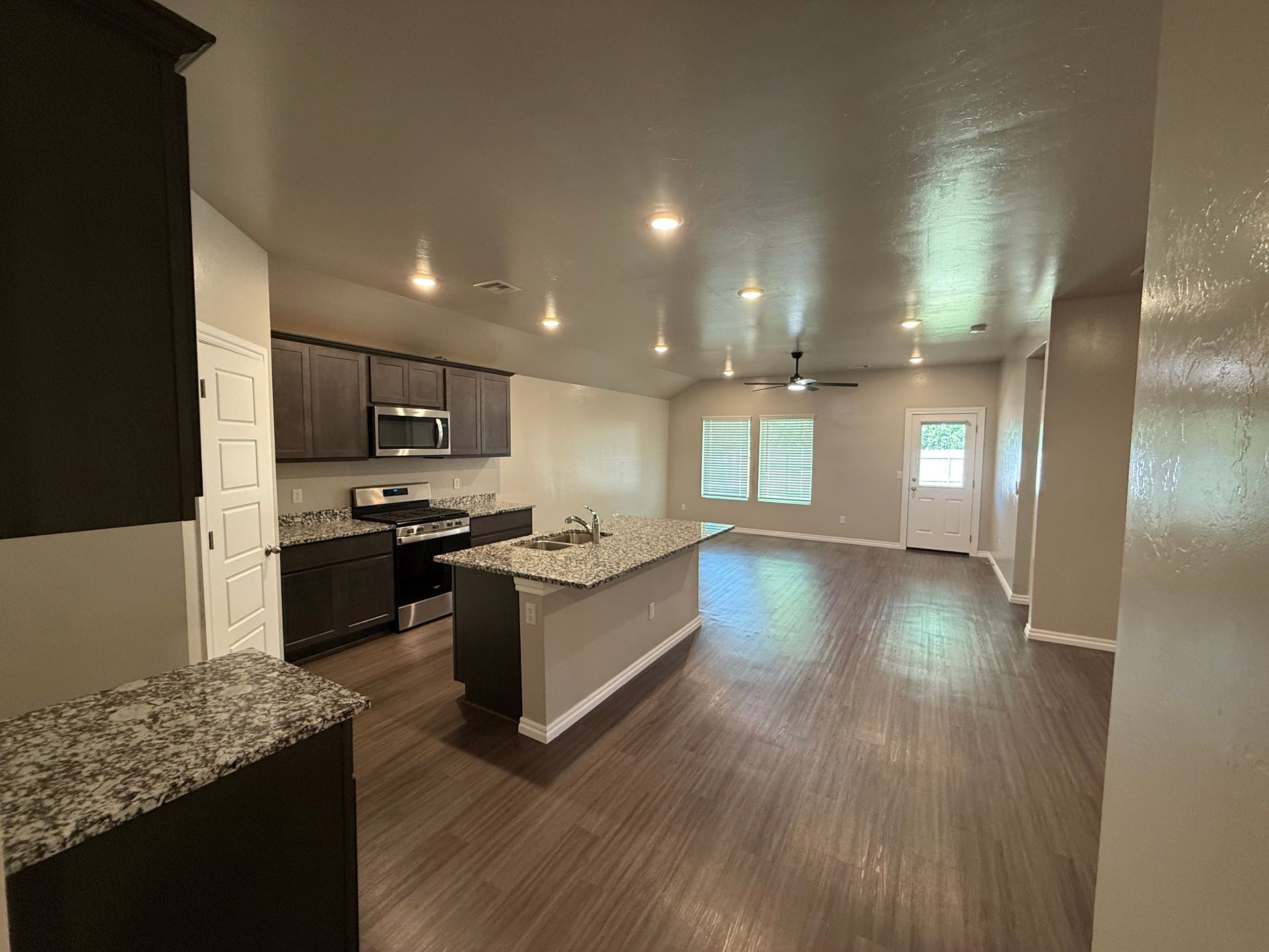 Modern kitchen with dark cabinets, granite countertops, island, and wood floors.