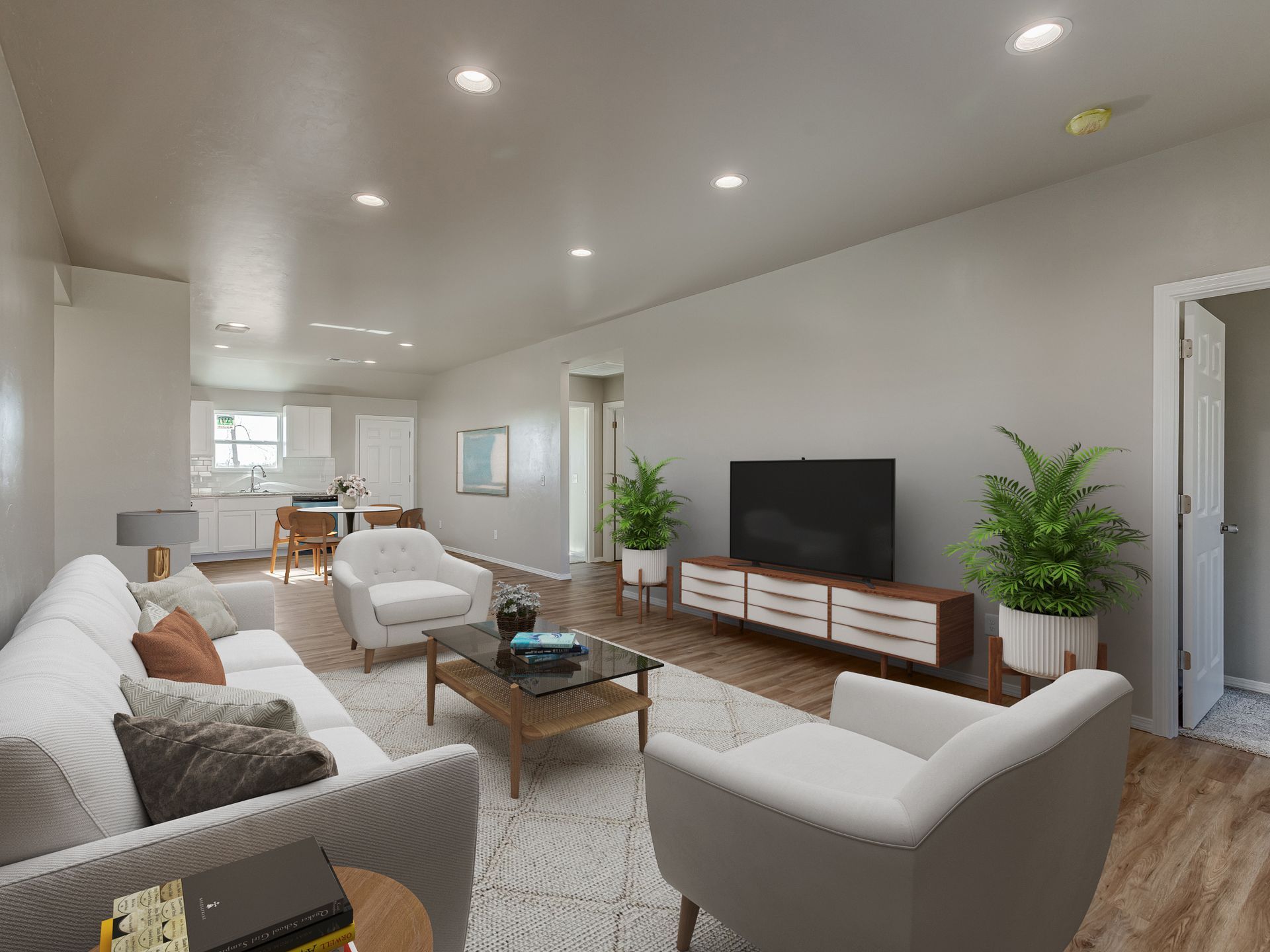 Living room with white sofa, chairs, TV, and plants. Bright, neutral colors.
