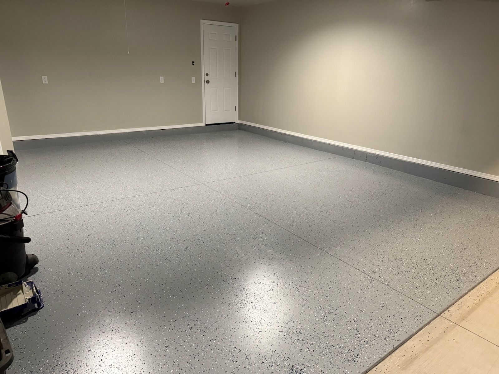 Garage interior with gray epoxy floor, beige walls, and white door.