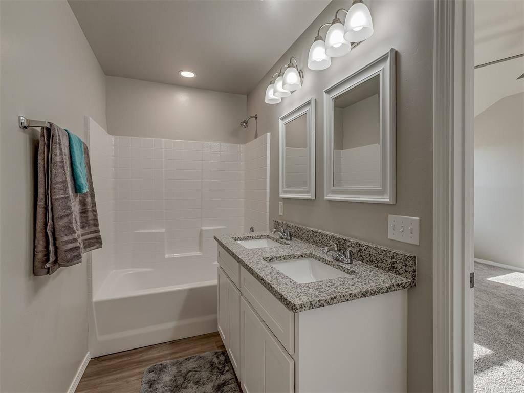 Bathroom with white vanity, gray countertop, white tub/shower, and gray walls.