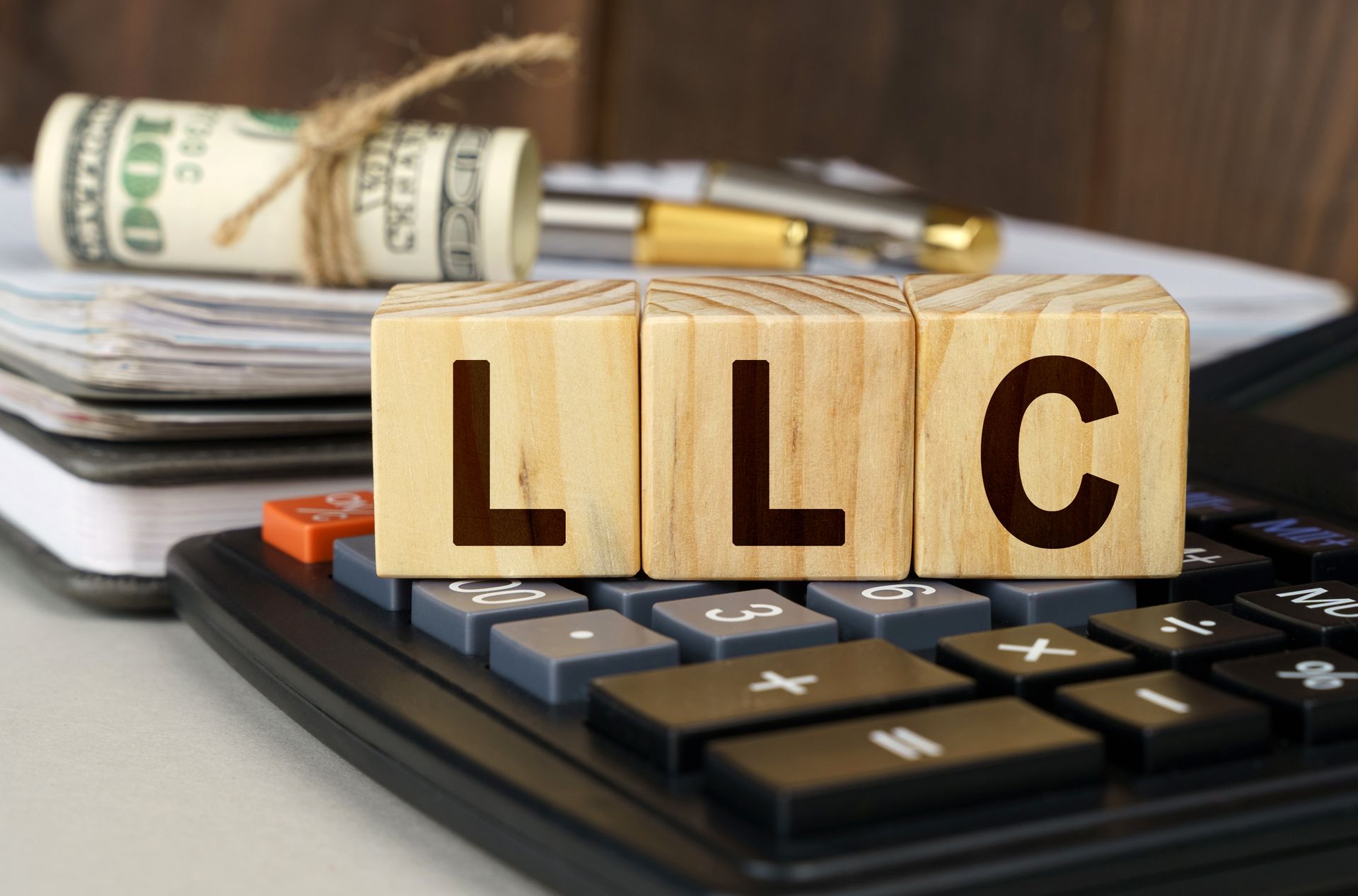 The word llc is written on wooden blocks next to a calculator.
