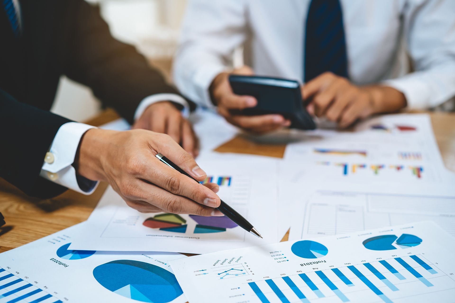 A group of business people are sitting at a table looking at charts and graphs.
