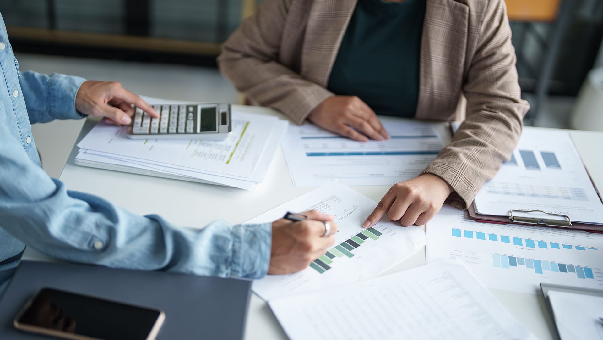 Two people are sitting at a table with papers and a calculator.