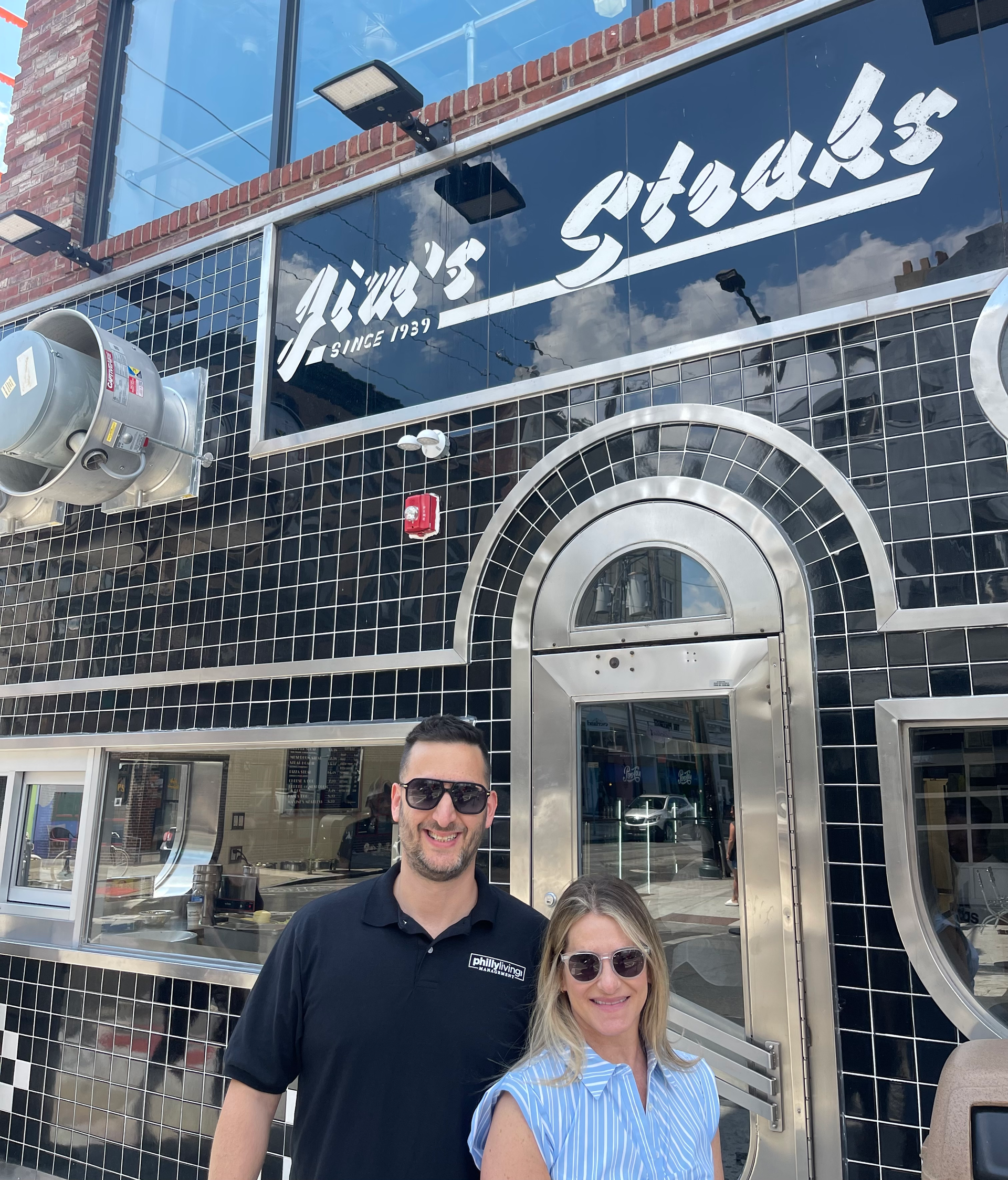 A man and a woman are standing in front of a restaurant.