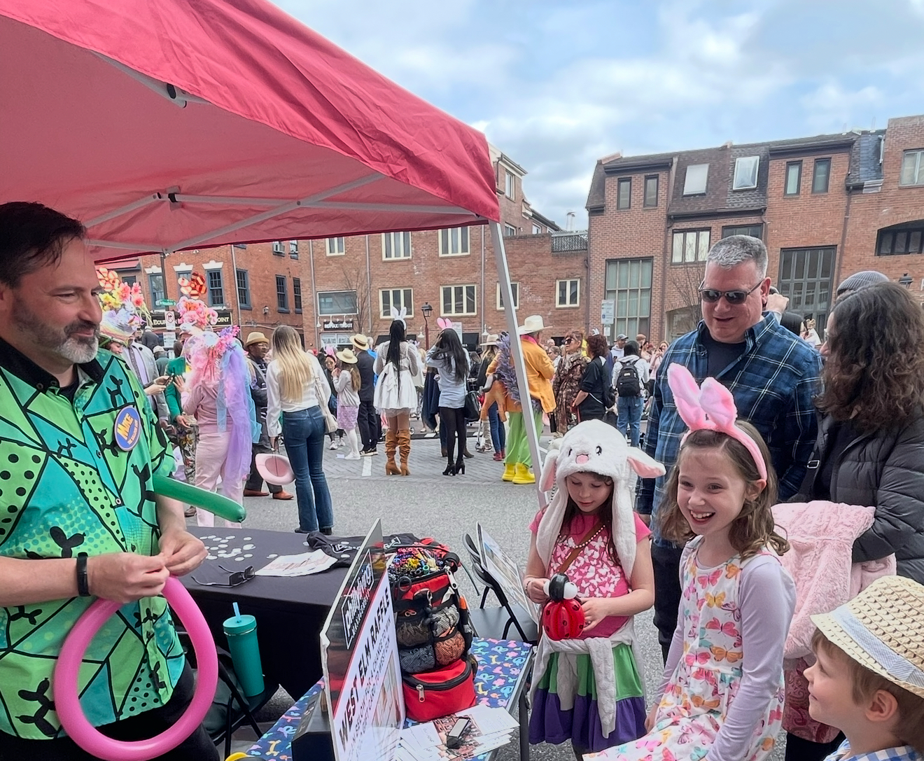 A man is holding a pink balloon in front of a crowd of people.