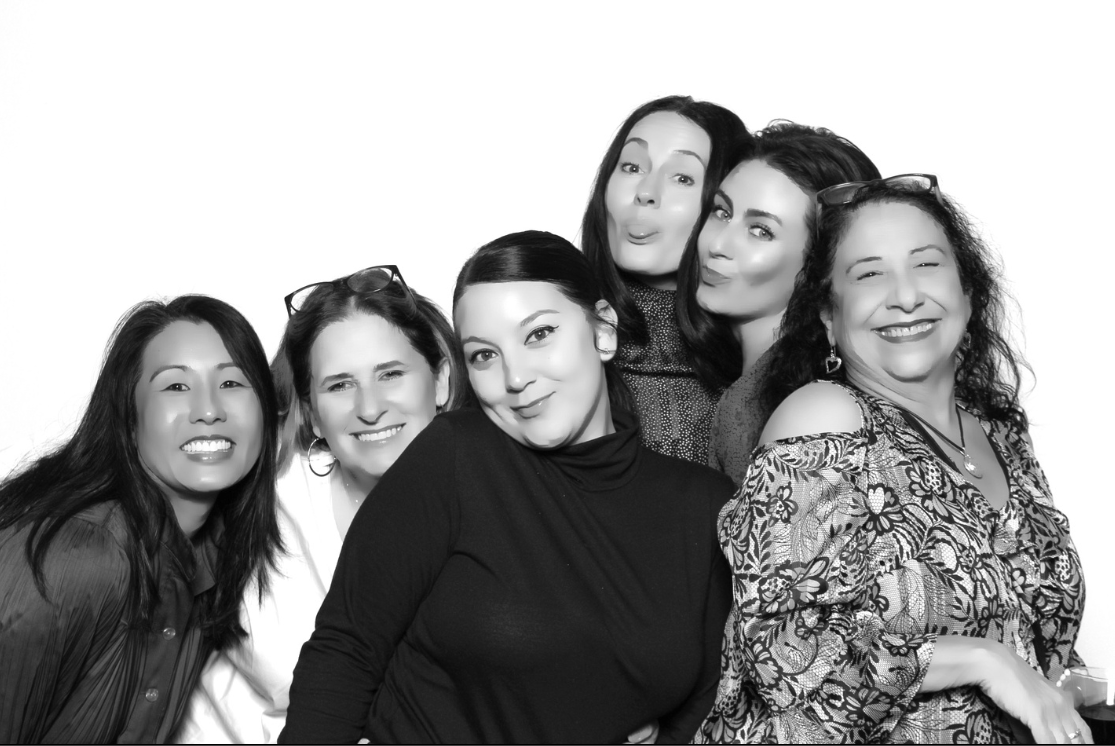 A group of women are posing for a picture in a black and white photo booth.