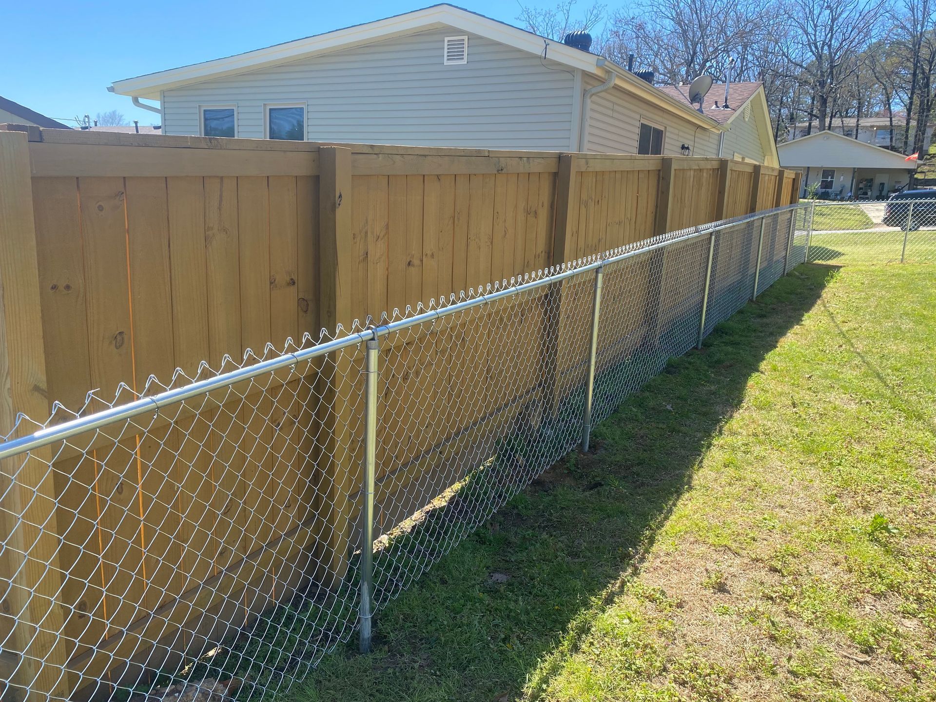 Wooden fence and chain-link fence side-by-side in a yard.