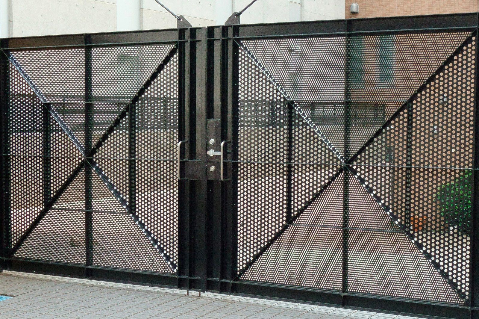 Black metal gate with diamond pattern and a central locking mechanism.