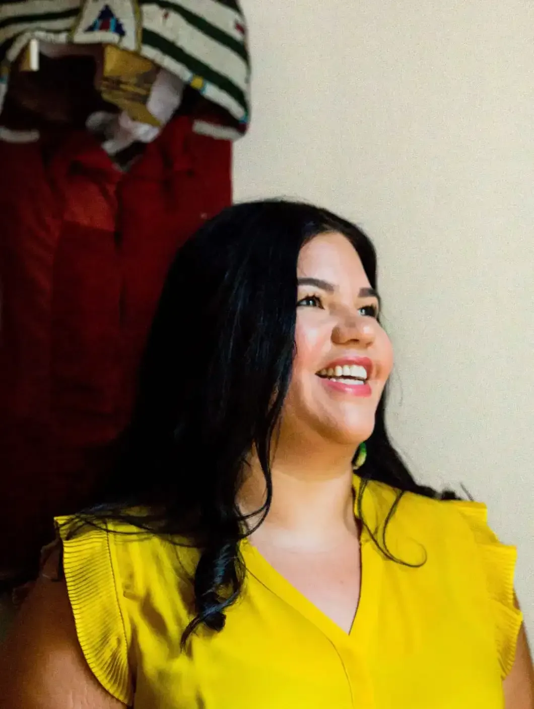 The woman is wearing a yellow shirt and smiling.