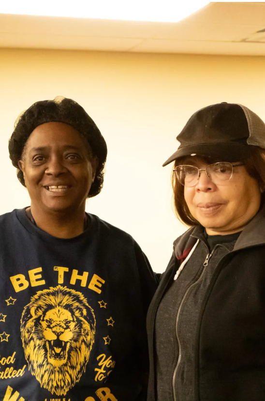 Two women posing for a picture with one wearing a shirt that says be the