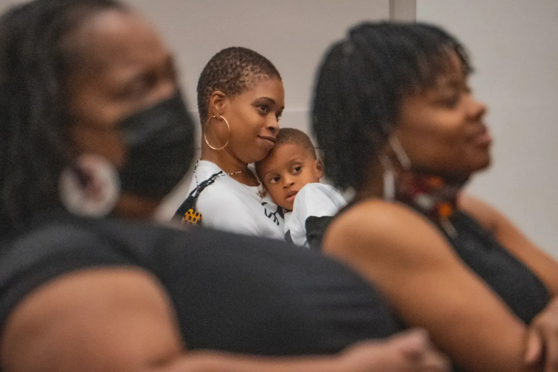 A woman is holding a baby in her arms while wearing a mask.