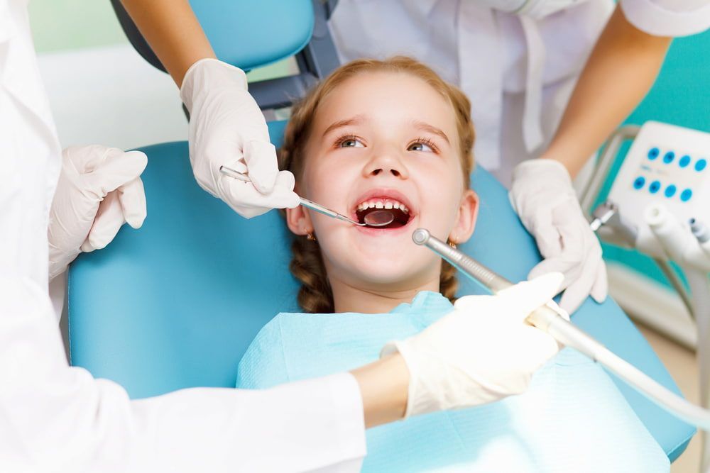 A Little Girl is Getting Her Teeth Examined by a Dentist — New Horizons Dental in Port Douglas, QLD