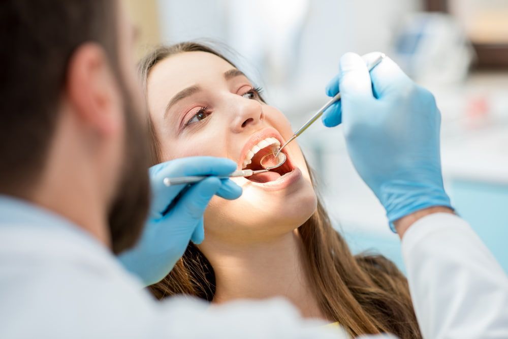 A Woman is Having Her Teeth Examined by a Dentist — New Horizons Dental in Port Douglas, QLD