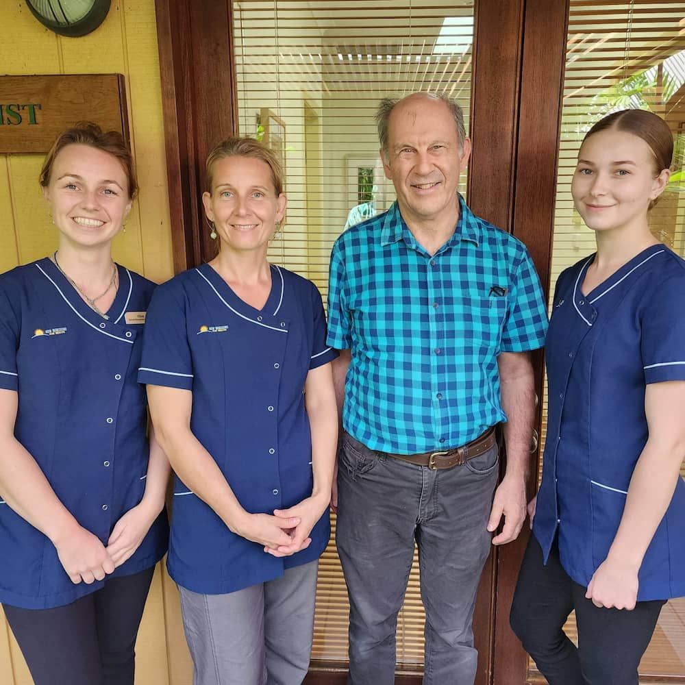 A Group of People Posing for a Picture in Front of a Sign That Says Dentist — New Horizons Dental in Port Douglas, QLD
