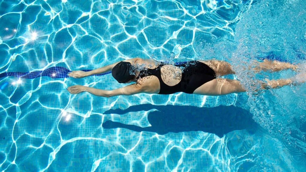 A Woman is Swimming in a Swimming Pool — New Horizons Dental in Port Douglas, QLD