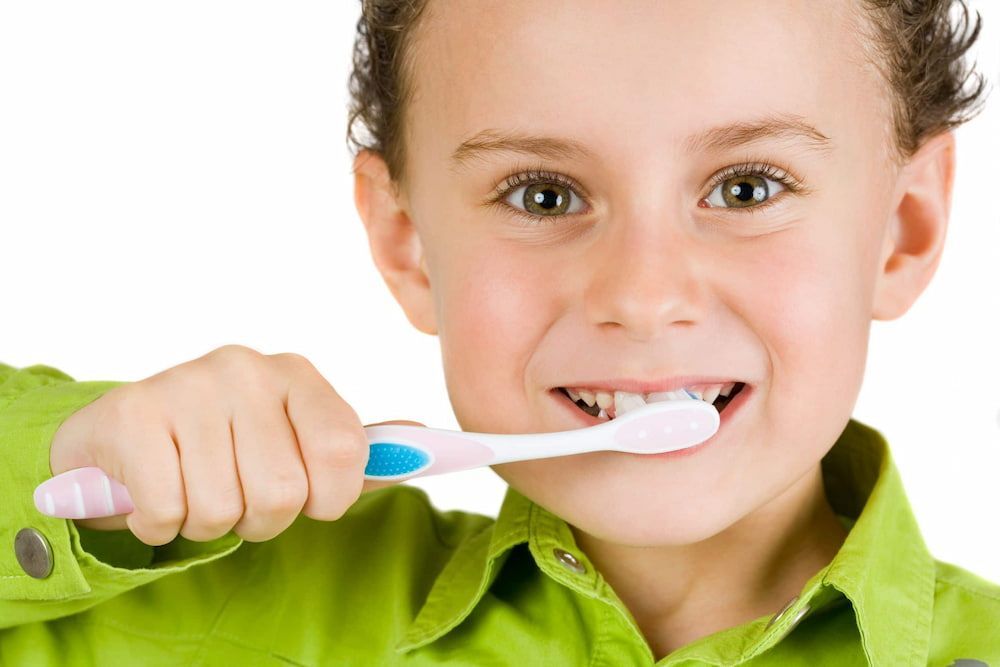A Young Boy is Brushing His Teeth With a Toothbrush — New Horizons Dental in Port Douglas, QLD