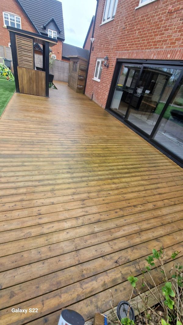 A wooden deck in front of a brick house with sliding glass doors.