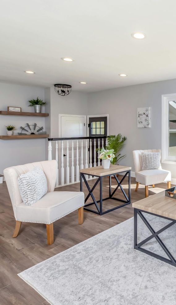 A living room with two chairs , a coffee table , and a staircase.