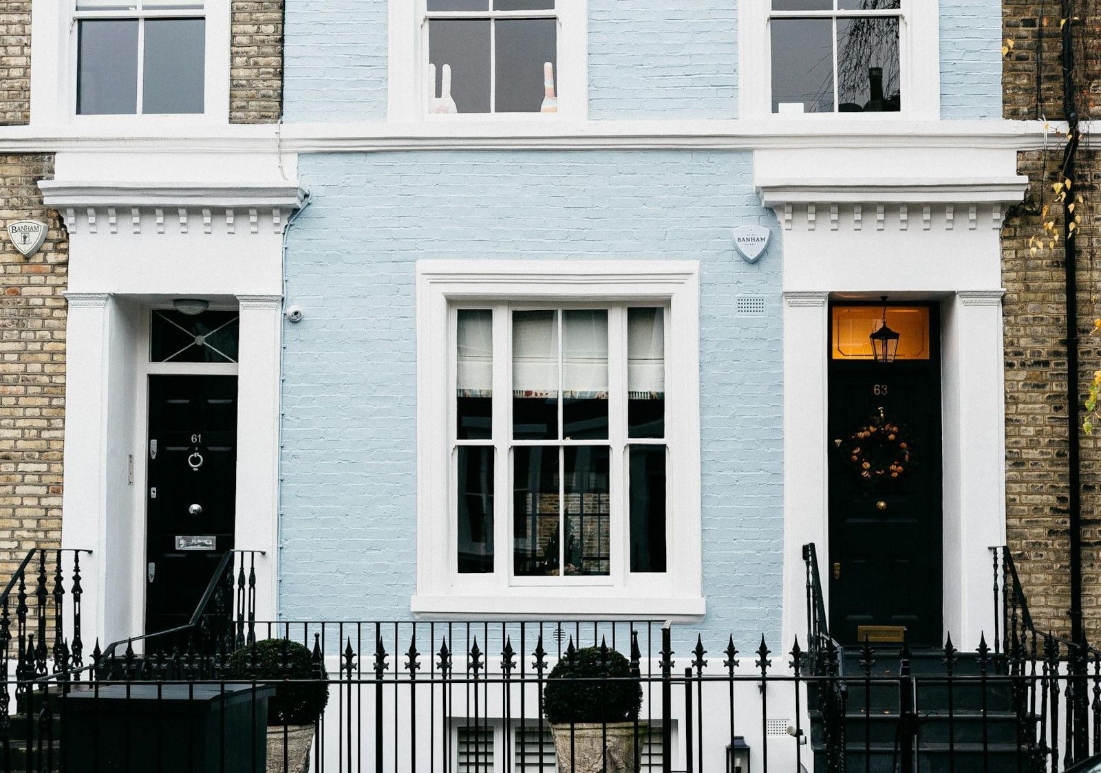 A blue and white brick house with black doors and windows.