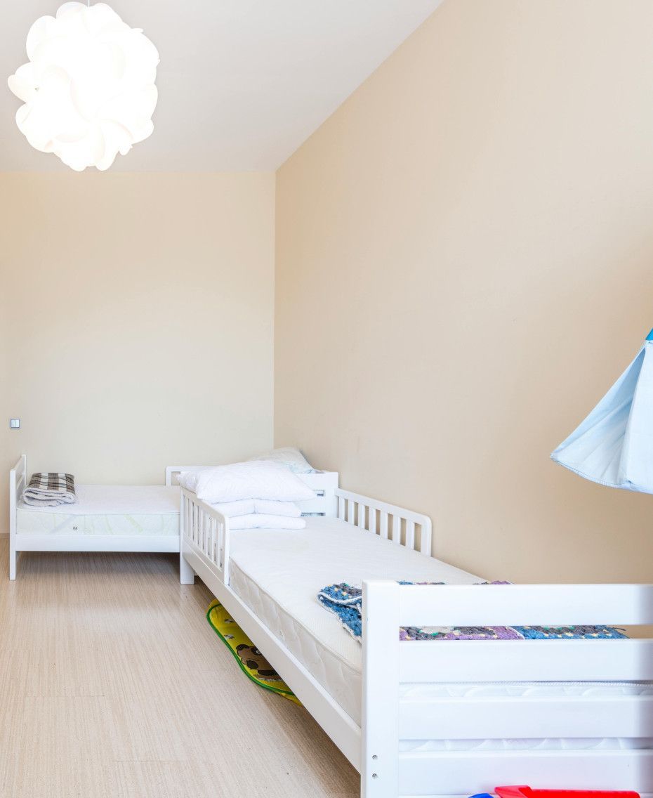 A bedroom with two beds and a lamp hanging from the ceiling