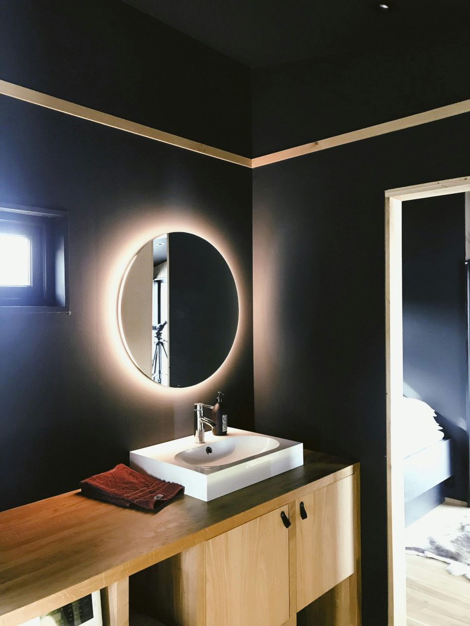 A bathroom with a sink and a round mirror