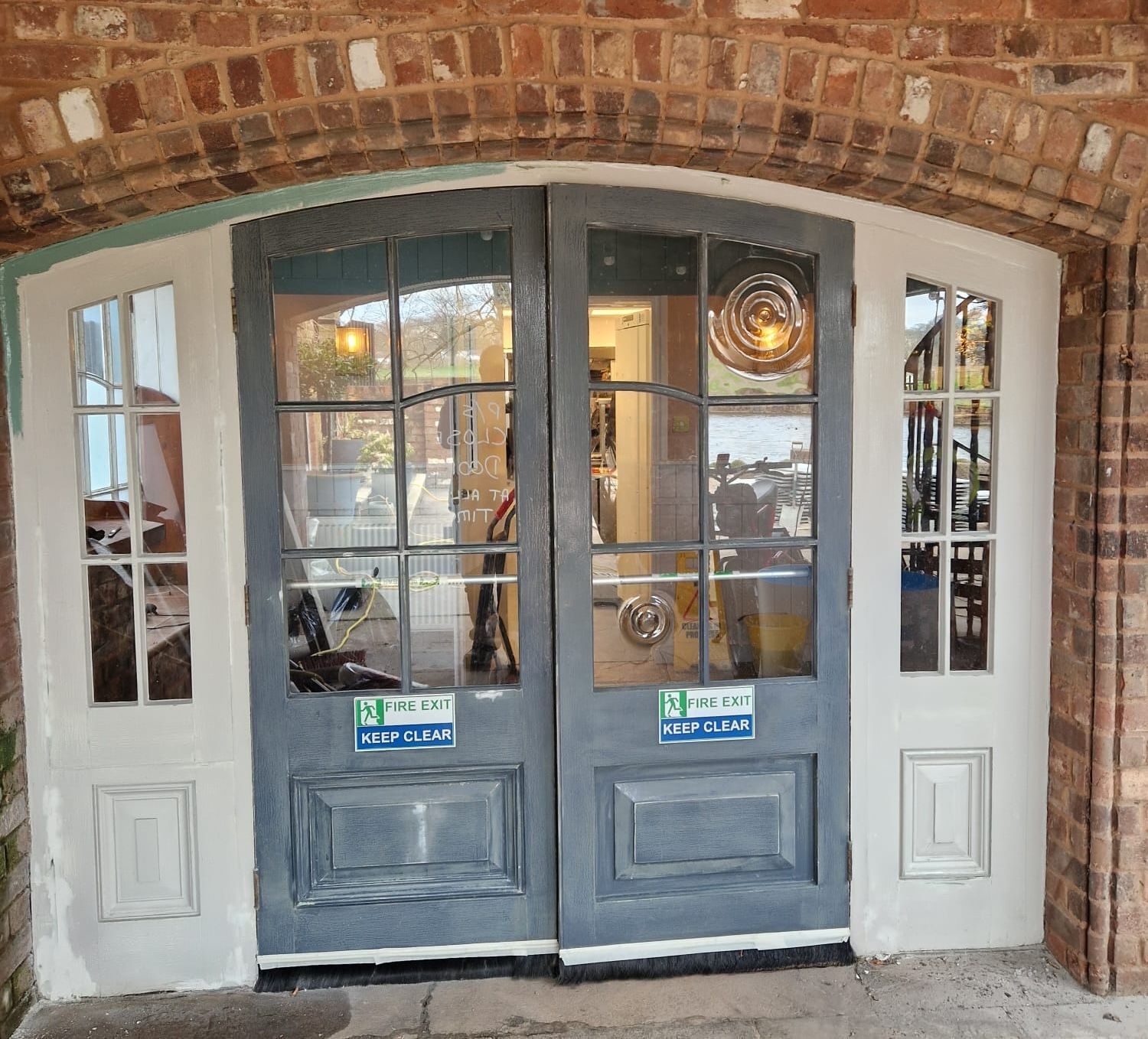 A pair of doors with a brick wall behind them.