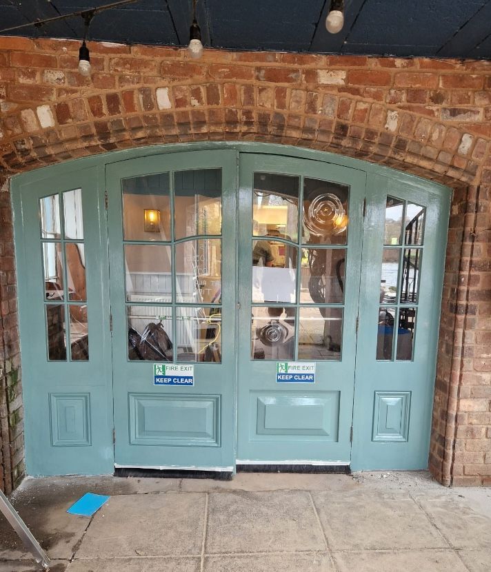 A brick building with a blue door and glass windows.