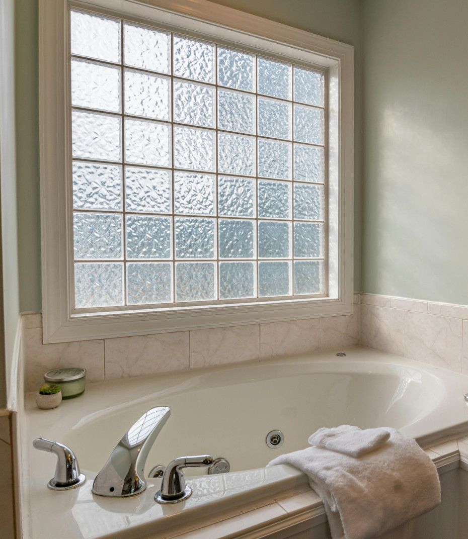 A bathroom with a jacuzzi tub and a window.