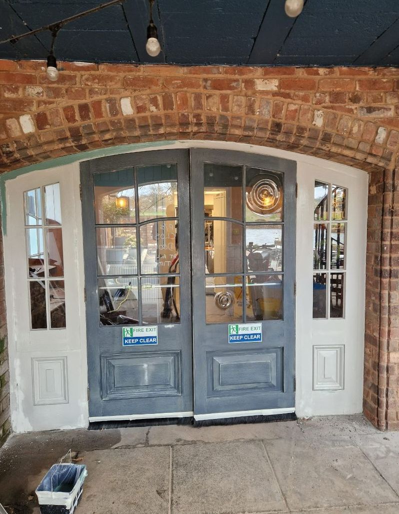 A brick building with a gray door and a white door.
