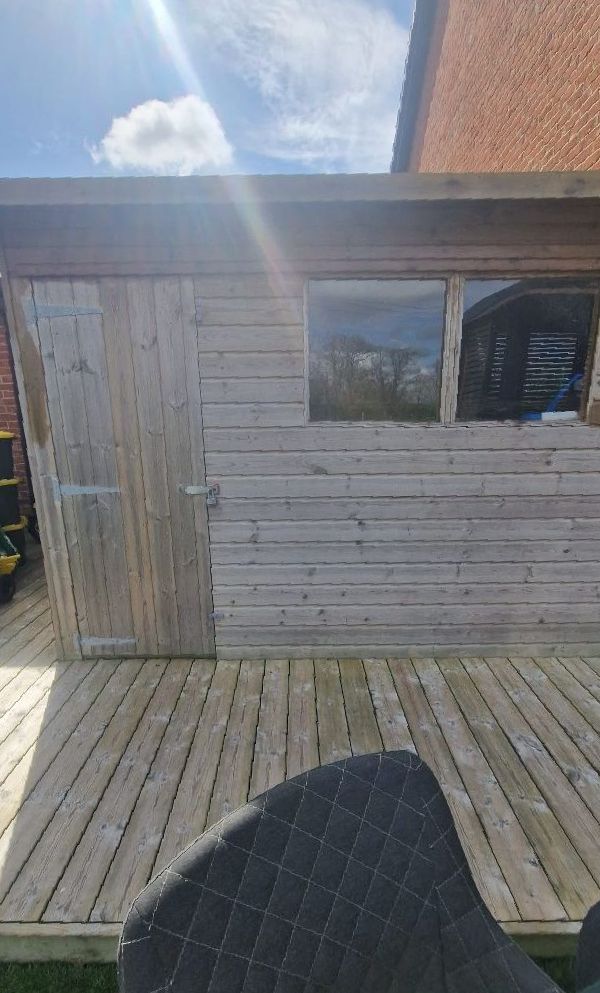 A wooden shed is sitting on top of a wooden deck.