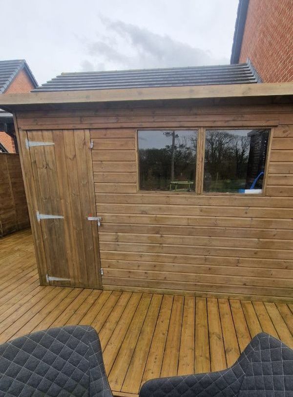A wooden shed is sitting on top of a wooden deck.