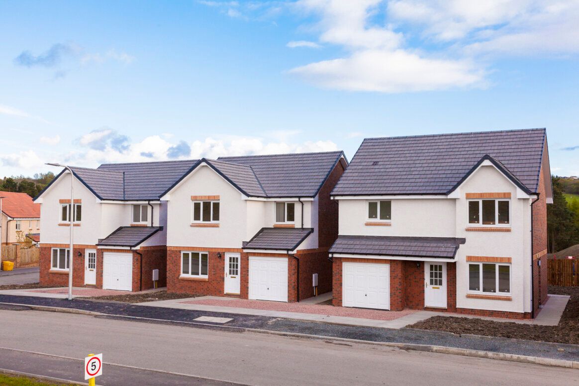 Three newly built, two-story houses with white siding, brick accents, and gray tile roofs under a blue sky.