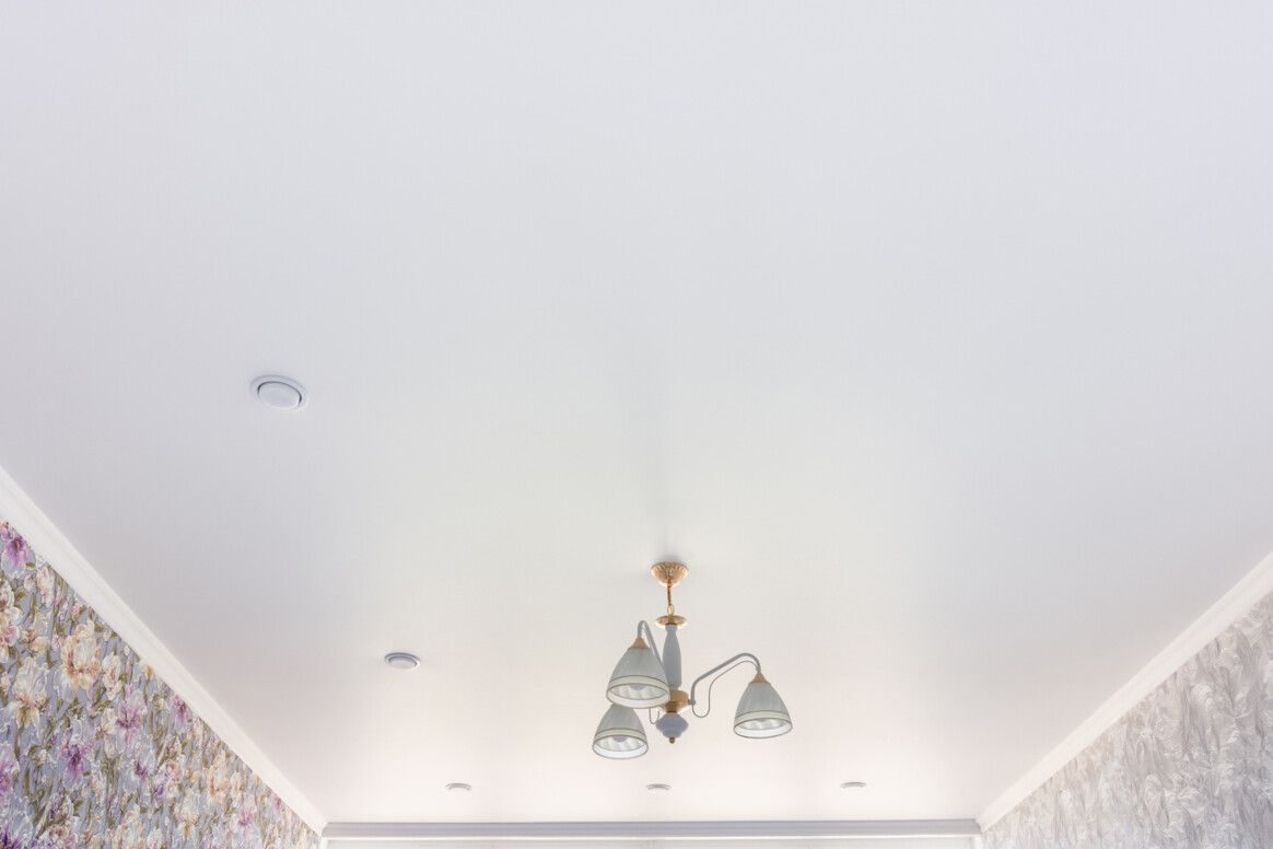 White ceiling with chandelier and wallpapered walls.
