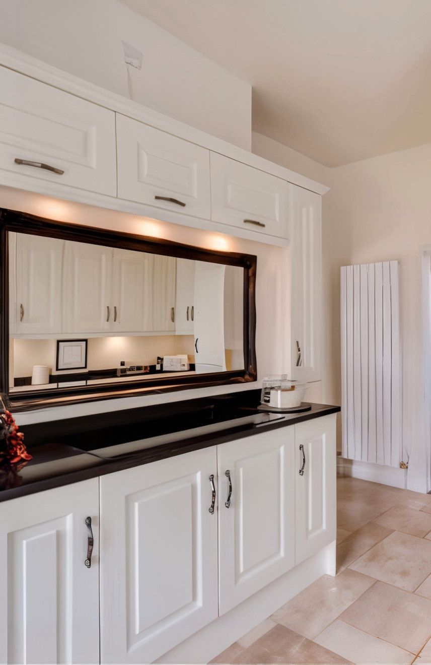 White kitchen cabinets with black countertop, mirror backsplash, and radiator.