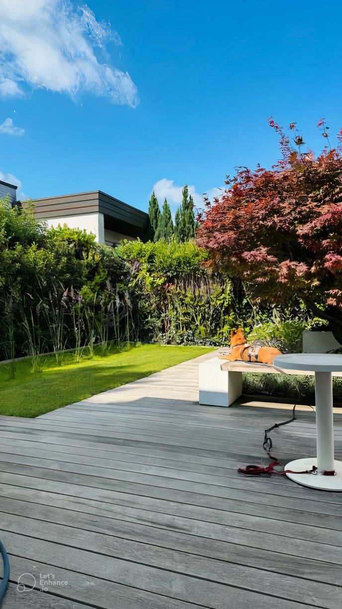 A wooden deck with a table and chairs in a garden.