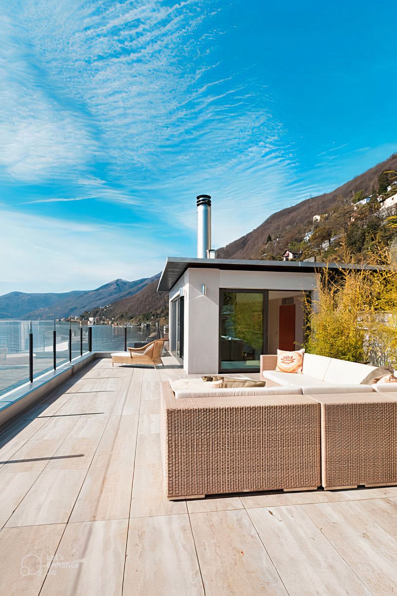 A large rooftop deck with a view of a lake and mountains.