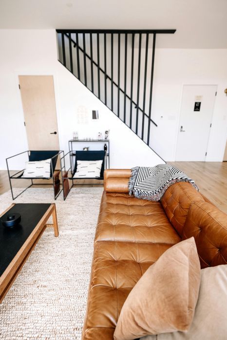 A living room with a brown leather couch and stairs. Staircase expertly painted by Rose Decor in Preston, UK.