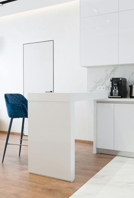 A kitchen with white cabinets and a blue chair.