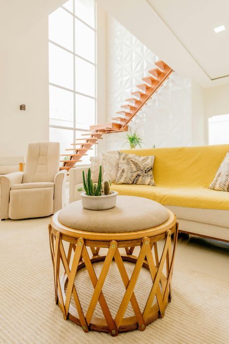 A living room with a yellow couch and a wooden staircase. Staircase expertly varnished by Rose Decor in Preston, UK.