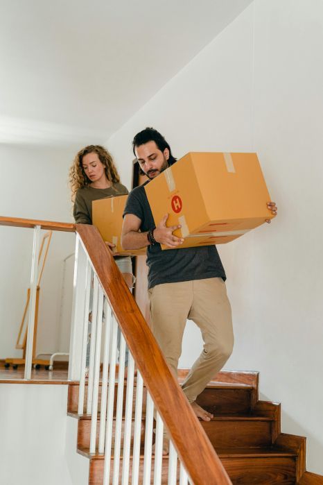 A man and a woman are carrying boxes up a set of stairs. Staircase expertly painted by Rose Decor in Preston, UK.