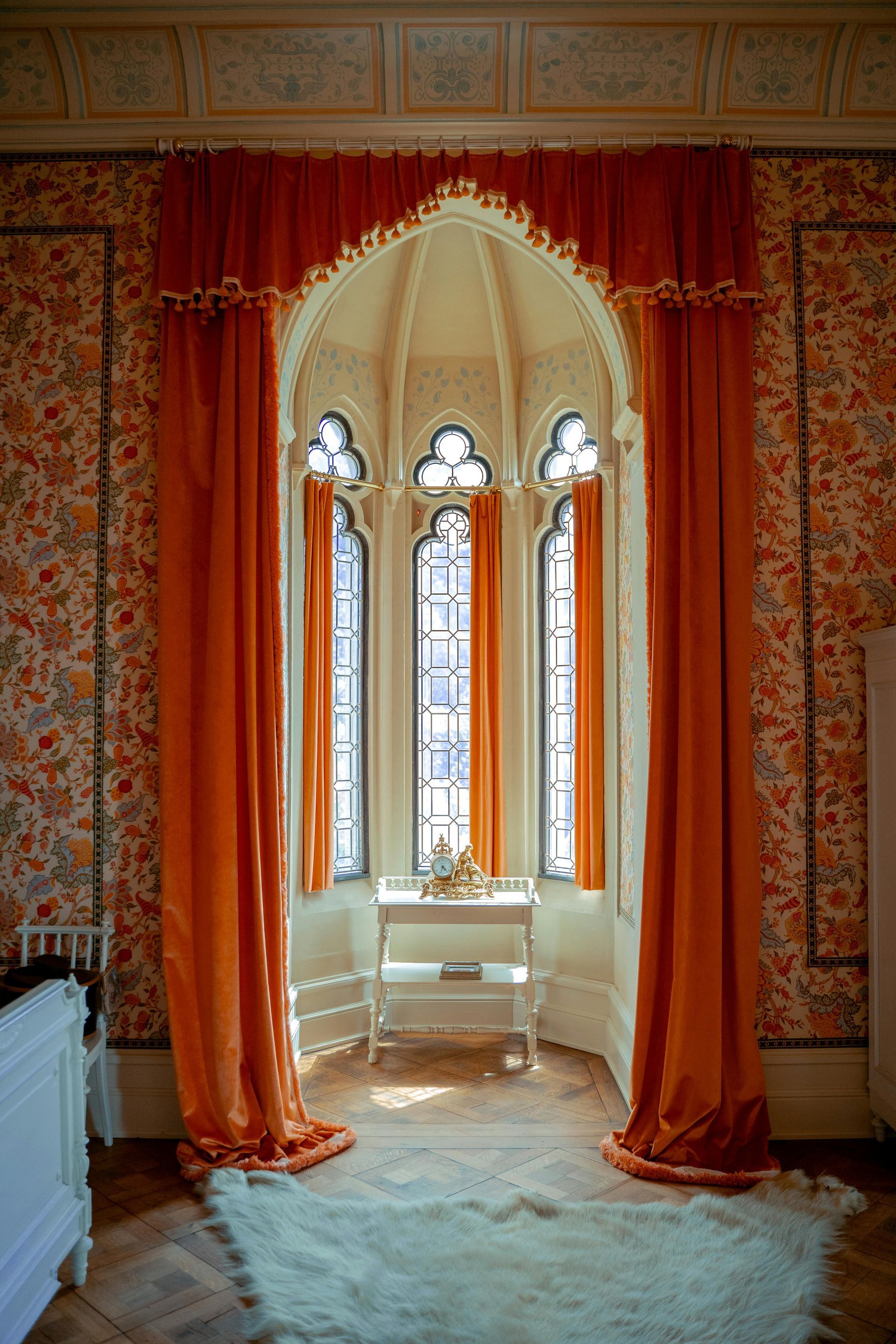 Room with floral red wallpaper and grand window with red drapes