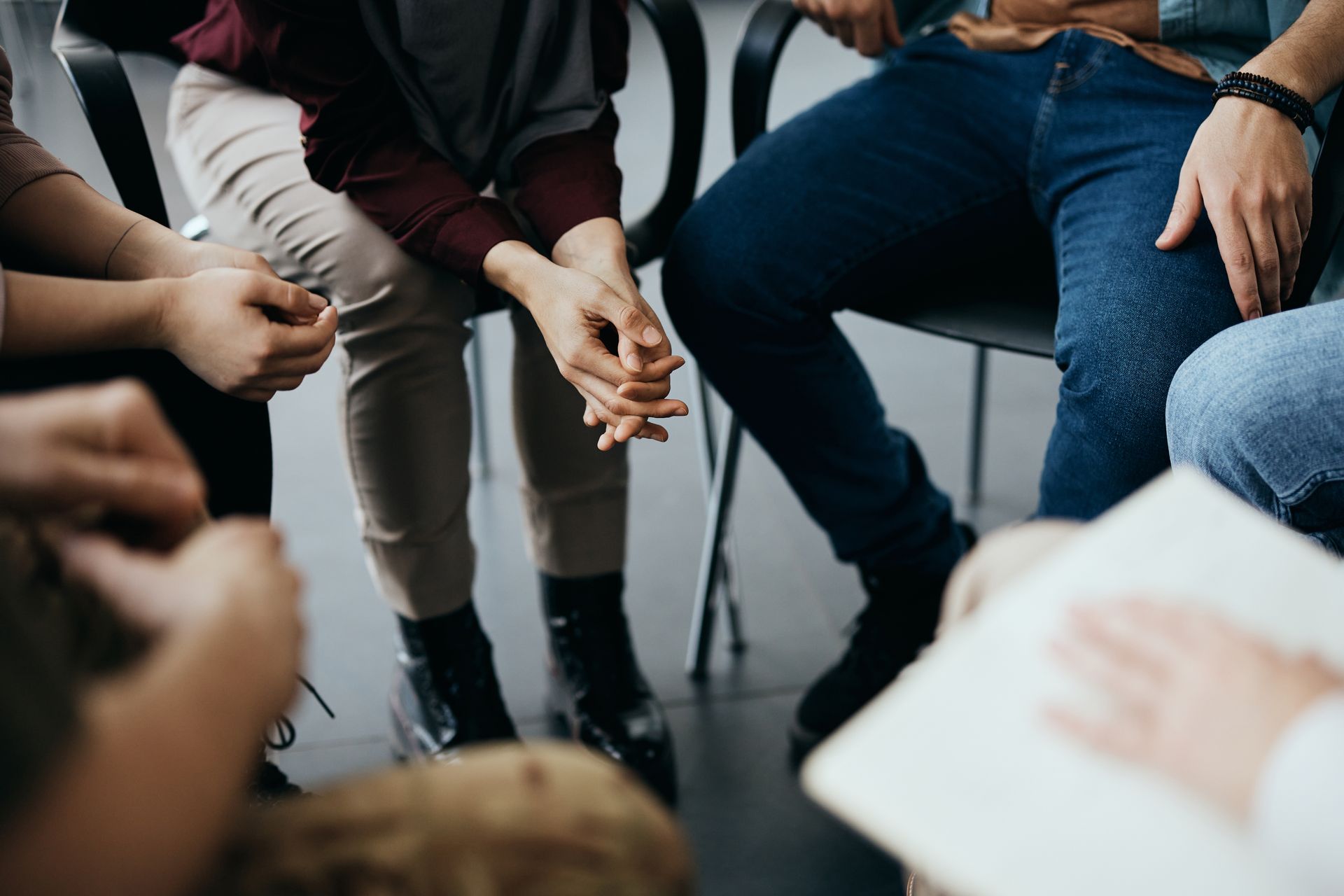 A group of people sitting in a circle, their hands resting in their laps, engaged in a support or discussion session. A group of people sitting in a circle, their hands resting in their laps, engaged in a support or discussion session.