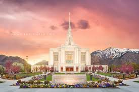 The Oquirrh Mountain Utah Temple at sunset, featuring a tall central spire, landscaped gardens, and snowy mountains.